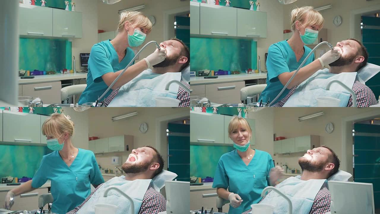 女牙医钻男性患者的牙齿，看着镜头。滑块镜头
