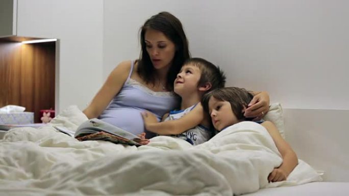 怀孕的妈妈，在床上为儿子们读睡前故事