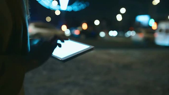 女人晚上在城市散步时使用触摸板
