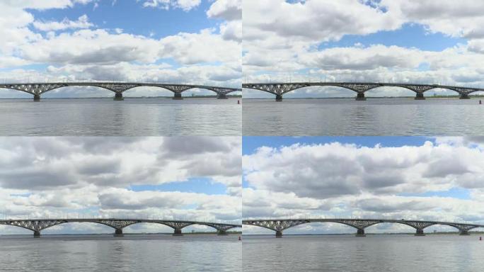 萨拉托夫市和恩格斯市之间横跨伏尔加河的公路桥。河流风景的时间流逝。漂浮在天空。桥上车辆的运动。夏日。