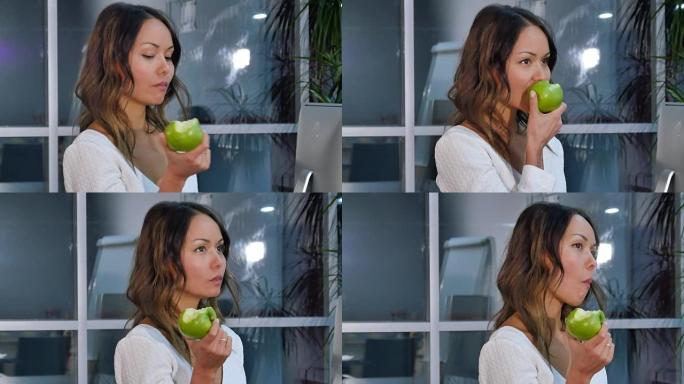 漂亮的女商人在办公室吃青苹果