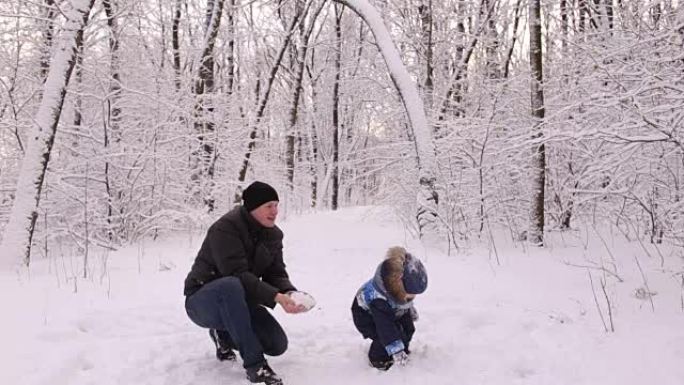 年轻的爸爸和他的小儿子在玩雪