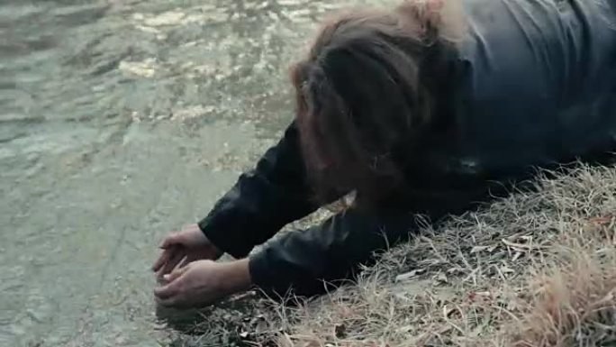 一个无家可归的乞丐躺在河边，洗手洗脸