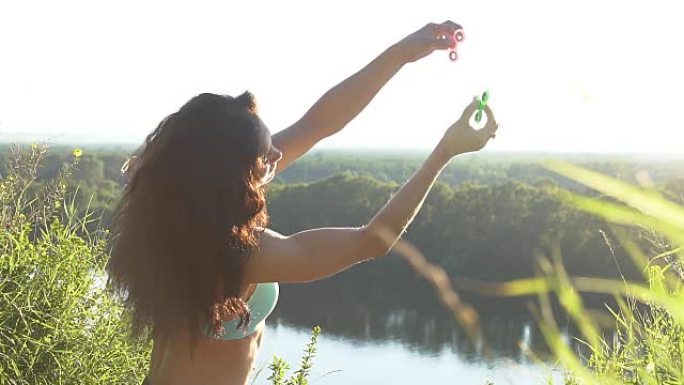 美丽的女人平衡拇指上的两个坐立不安的旋转器，慢动作