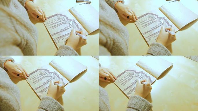 一名年轻女子打开记号笔，开始在相册中画画。