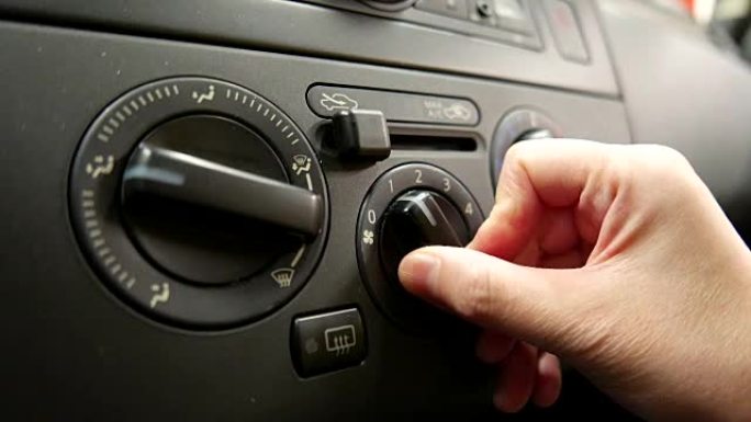 打开和调节汽车气候控制按钮的手转动汽车加热器的运动