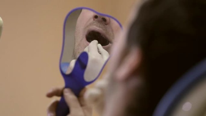 女牙医向她展示了一颗有问题的牙齿，看着一个镜子病人。