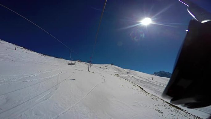 从升降椅上从顶部到底部观看积雪覆盖的滑雪场，痕迹，滑雪者和副飞机。第一人称视角
