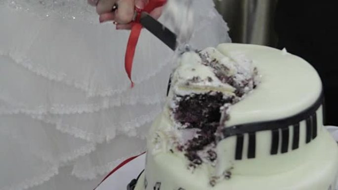 新娘和新郎的手切成一块结婚蛋糕。切结婚蛋糕。人们切蛋糕，把蛋糕放在盘子里。白色和巧克力蛋糕。刀。婚礼