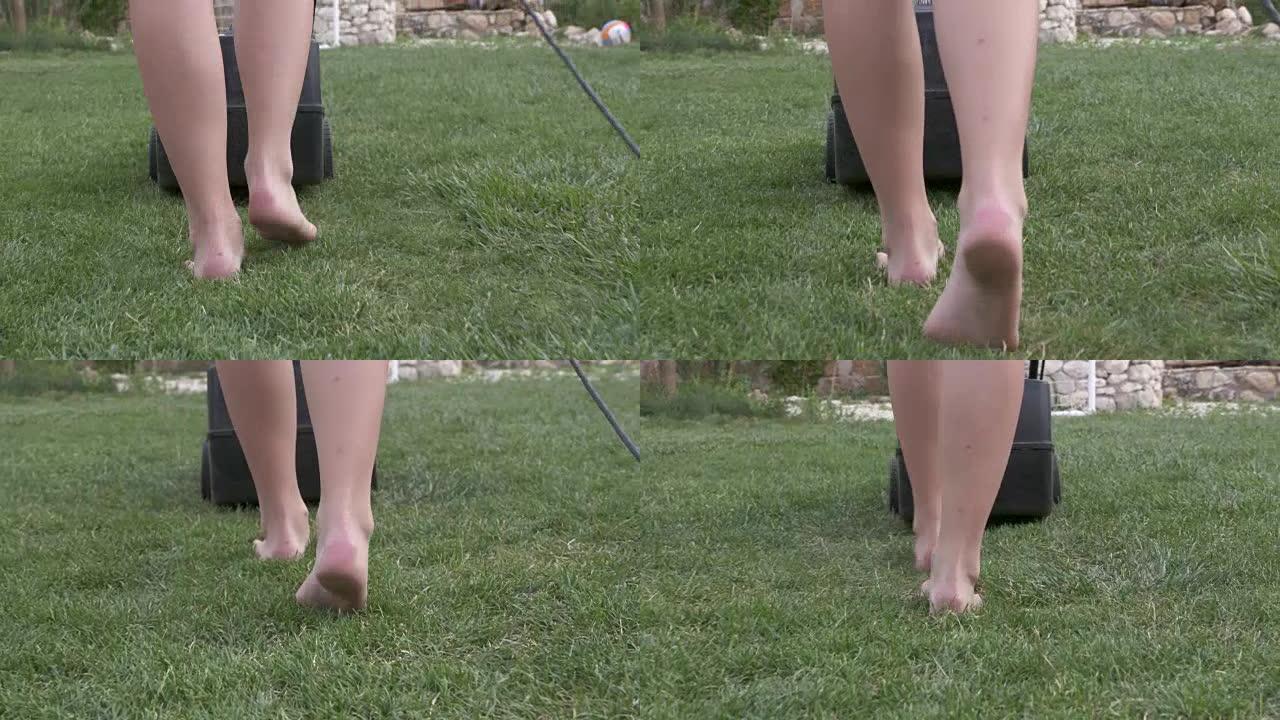 赤脚年轻女孩在花园里用割草机割草