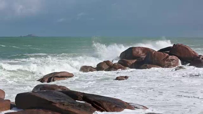 海浪在沿海粉色石头巨石上破碎。