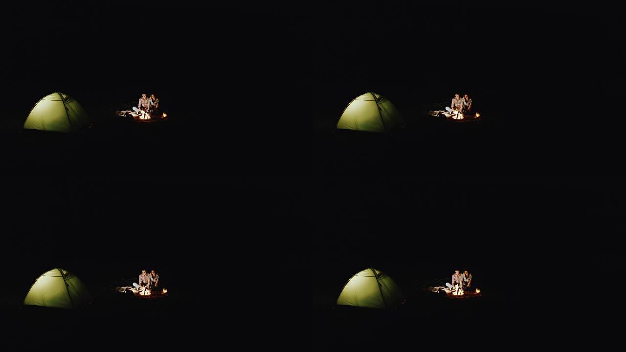 一对年轻夫妇的顶视图帐篷和篝火。天黑了，只有火和帐篷让人们精神焕发