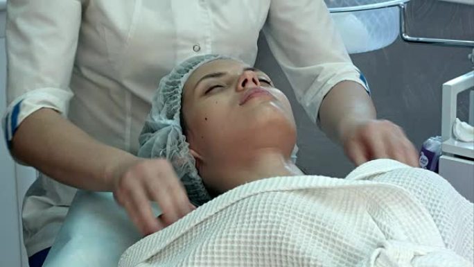 在水疗中心接受面部和颈部按摩的年轻女子