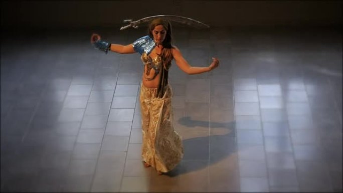 一名妇女穿着传统民族服装，头上戴着剑跳舞
