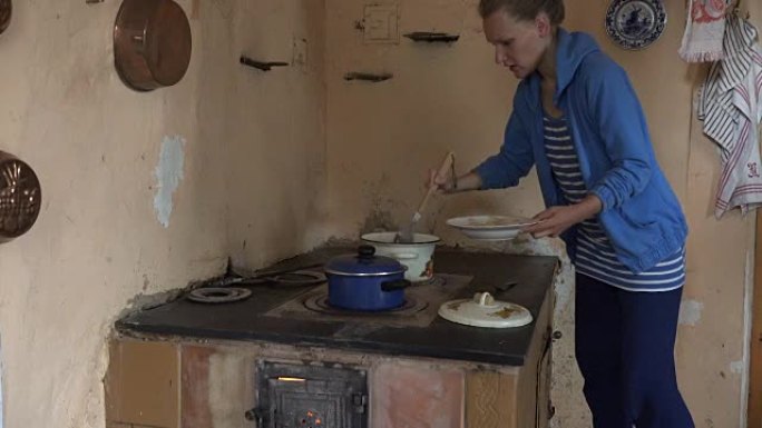 丫头女人在复古炉子上从沸腾的锅里摘下煮熟的饺子。