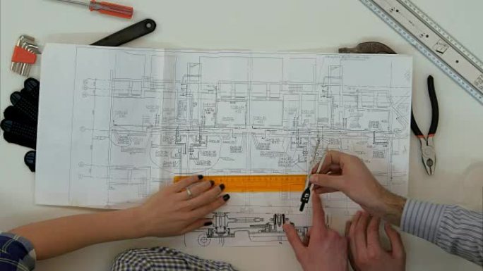 年轻的建筑师用分尺和尺子检查图纸尺寸