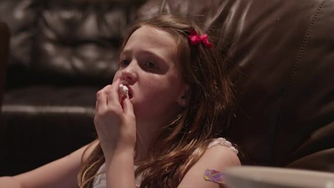 一个年轻的女孩在家庭影院看电影爆米花