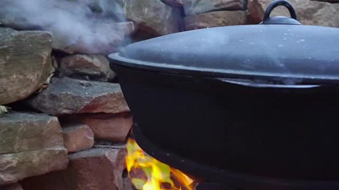 用铸铁大锅在火上煮肉。
