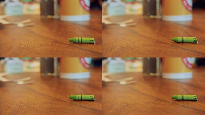棕色木桌上的绿色粉彩蜡笔卷