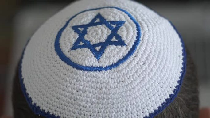 白色的基帕 (kipah) 和蓝色的玛格·大卫 (Magen David) 在男人的头上，象征着犹太