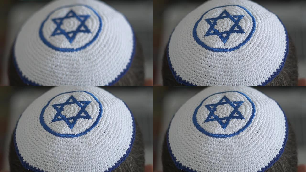 白色的基帕 (kipah) 和蓝色的玛格·大卫 (Magen David) 在男人的头上，象征着犹太
