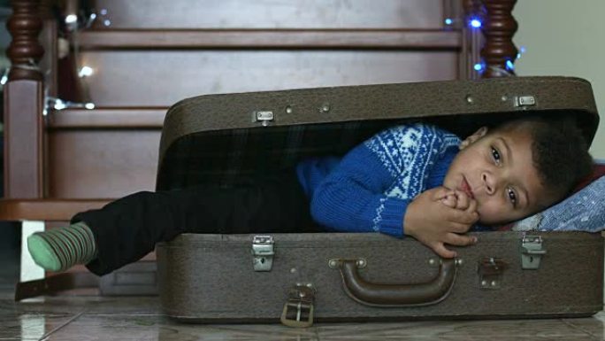 微笑的孩子躺在手提箱里。