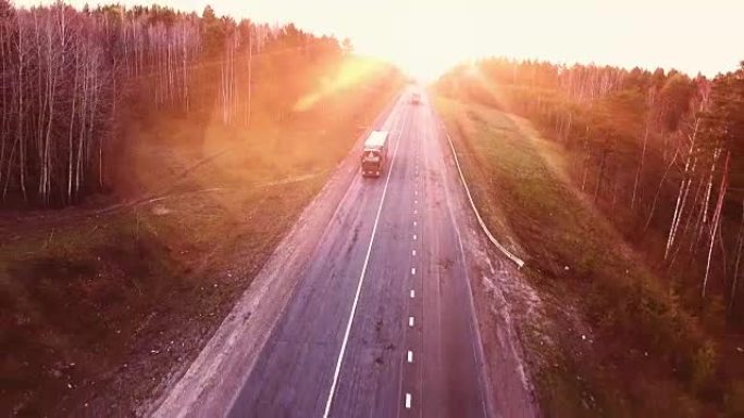 日落时高速公路上方的航班。道路上卡车的鸟瞰图