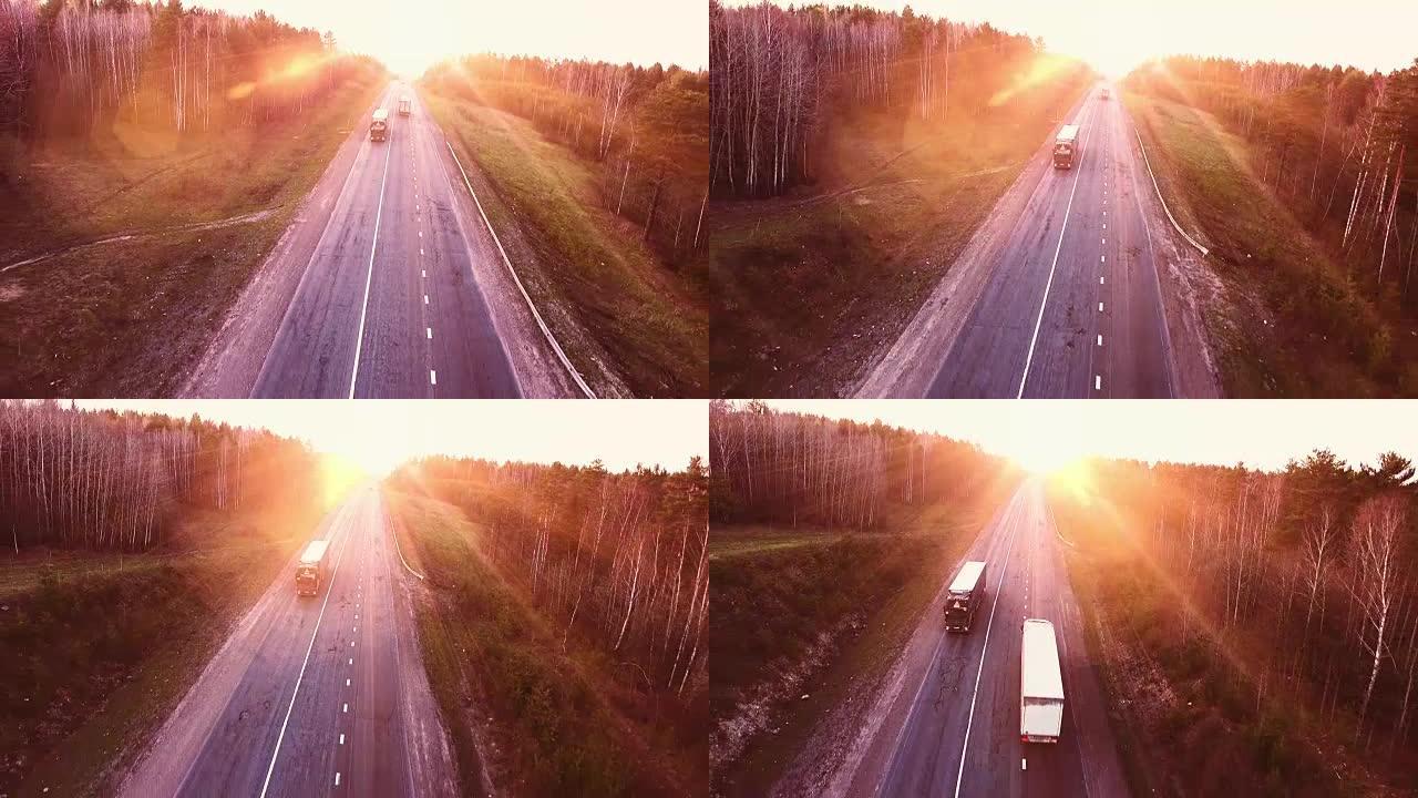 日落时高速公路上方的航班。道路上卡车的鸟瞰图
