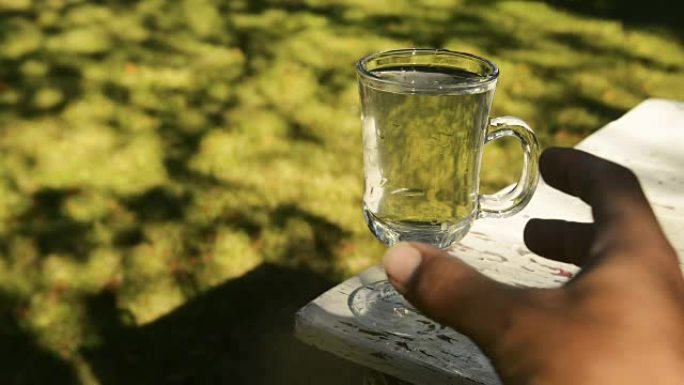 在炎热的夏日里，用手从旧桌子上拿一杯水