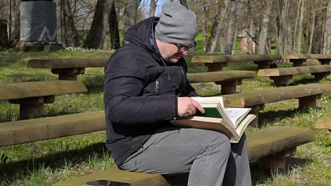 男人在公园的长凳上读两本书