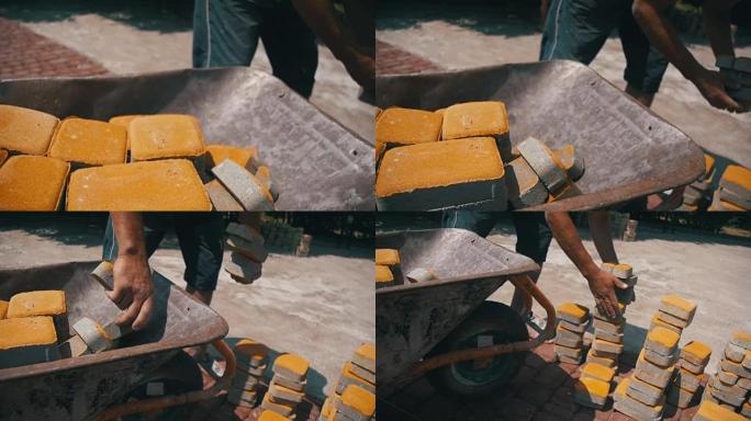 在建筑工地，建筑工人从独轮车上卸下石头铺路。慢动作
