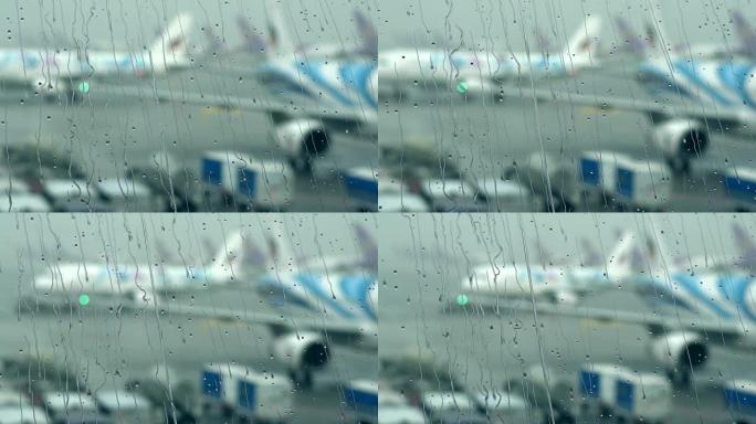 机场航站楼窗户上的雨滴，外面模糊机场。慢动作