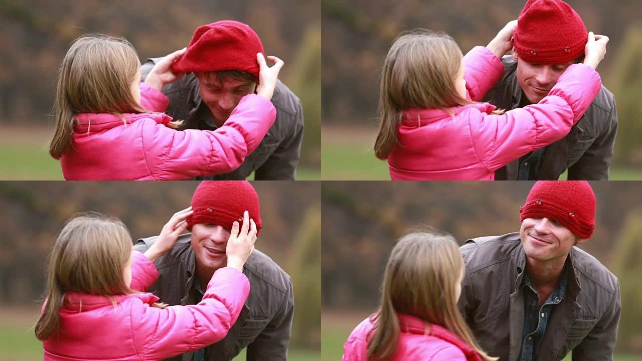 女孩把帽子放在爸爸的头上