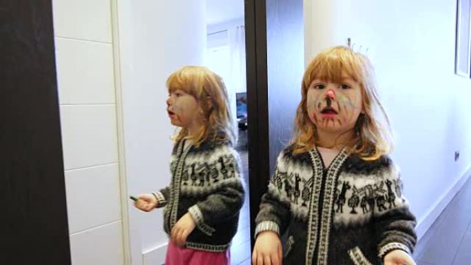 快乐的孩子画她的脸看着镜子