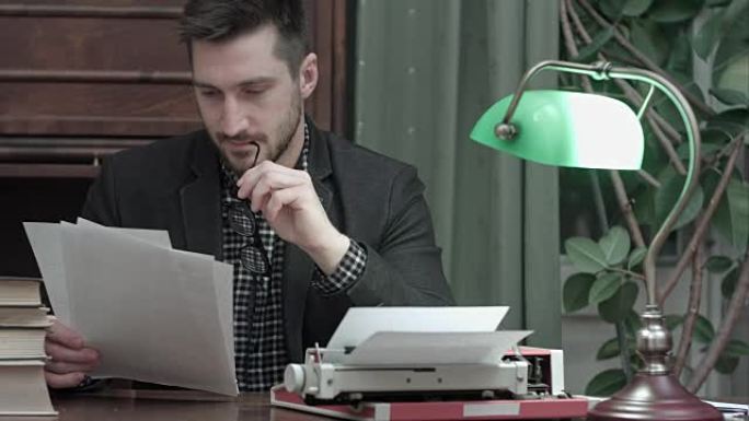 年轻记者拿着打字机坐在办公桌前阅读印刷文章