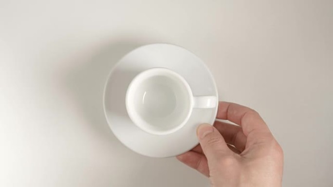 俯视图: 人手将白色咖啡杯放在白色桌子上