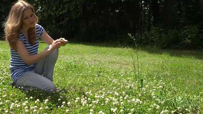 夏天，年轻女子编织三叶草皇冠蹲在草地上