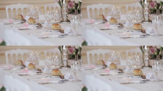 节日餐桌的餐具装饰布置关闭更换货架焦点细节。婚礼接待台，配有客人位置卡片，配有餐具花和盘子上的面包