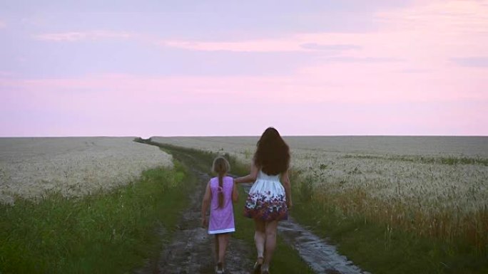 家庭晚上步行的母亲和女儿，在麦田里的道路上，孩子和母亲都在与黑麦穿过田野的道路上。