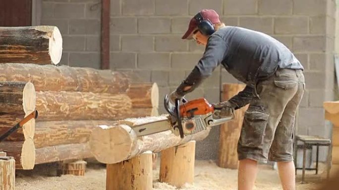 男人为未来的小木屋切断了光束电锯。木结构建筑工程