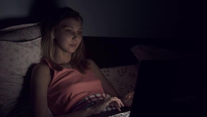 年轻女子在床上使用笔记本电脑