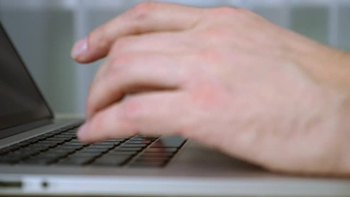 人的手在笔记本电脑键盘上打字。极端近距离手指在键盘上键入文本。