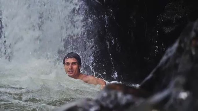 帅哥在热带丛林瀑布的溪水下放松。慢动作。1920x1080，高清