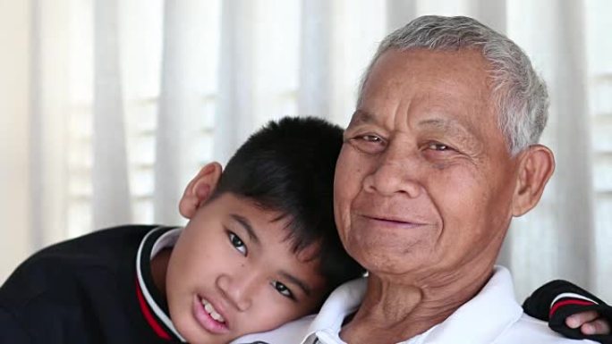亚洲退休的祖父和侄子或孙子，年轻的男孩拥抱在一起快乐地住在家里，家庭成员之间的关系得到温暖的家庭的保