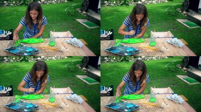 年轻艺术家女人在院子里的木桌上画鱼装饰