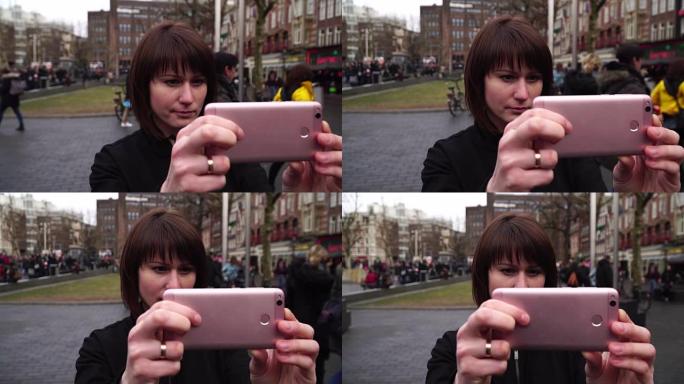 女游客在智能手机上拍摄城市照片。阿姆斯特丹伦勃朗普莱因。慢动作
