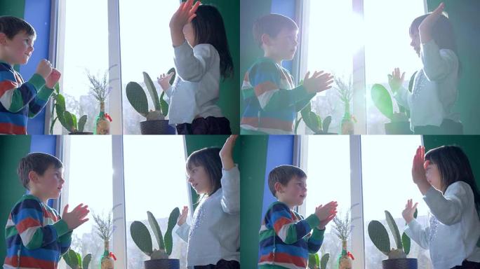 可爱的男孩和小女孩在假期对着大窗户玩拍手游戏