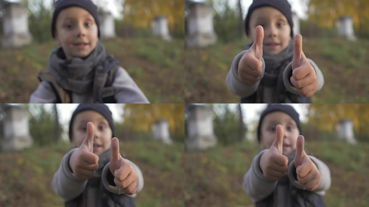 在顶部显示像手指一样的手势。微笑的小男孩在公园里玩耍。秋天。拇指