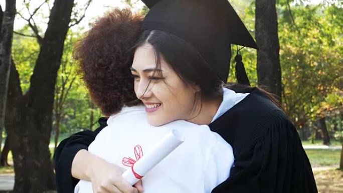 年轻的亚洲女学生在大学里戴着毕业帽和礼服，有毕业概念的女人。女人带着幸福的心情拥抱母亲。