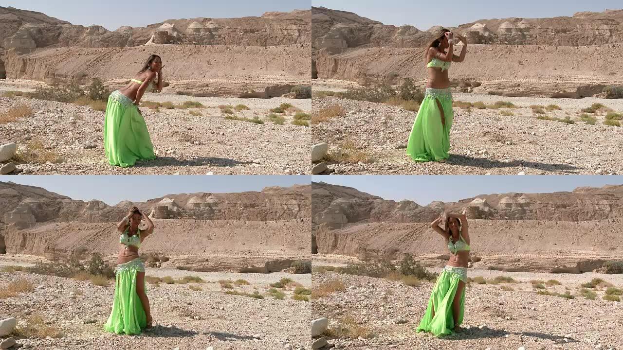漂亮的女舞者。肚皮舞。沙漠。性感的绿裙舞。全景
